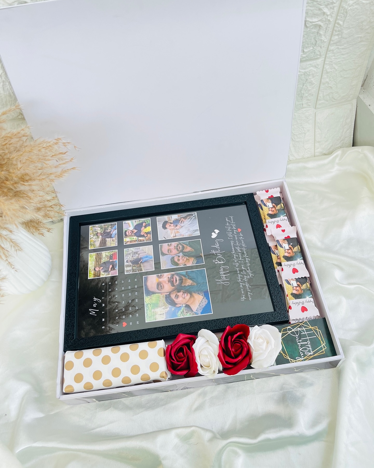 An elaborate birthday keepsake box built around a personalized couple photo-calendar frame, custom photo-wrapped chocolates, and silk roses.