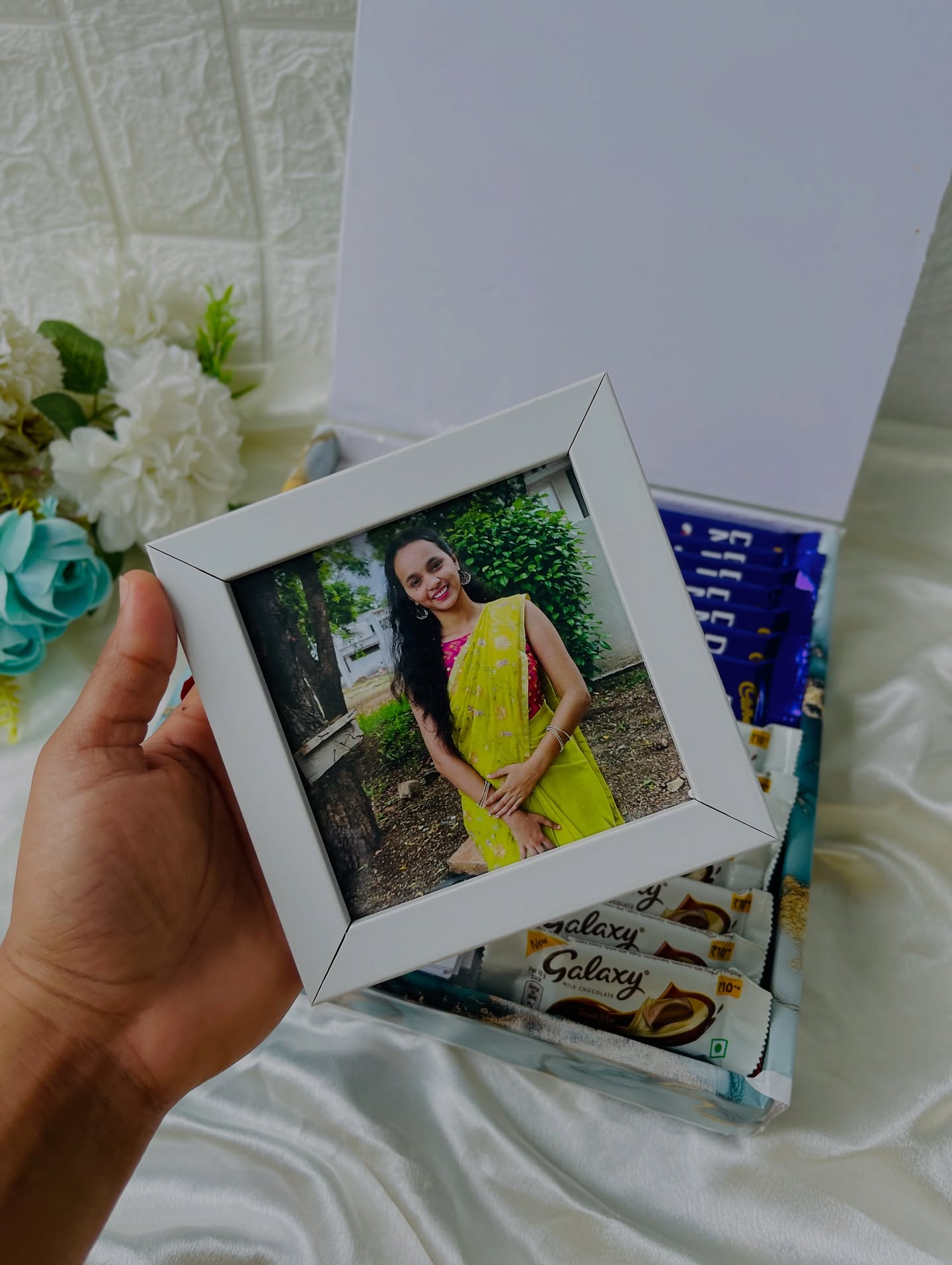 A gift box lined with Cadbury and Galaxy chocolate bars alongside a mini personalized photo frame.
