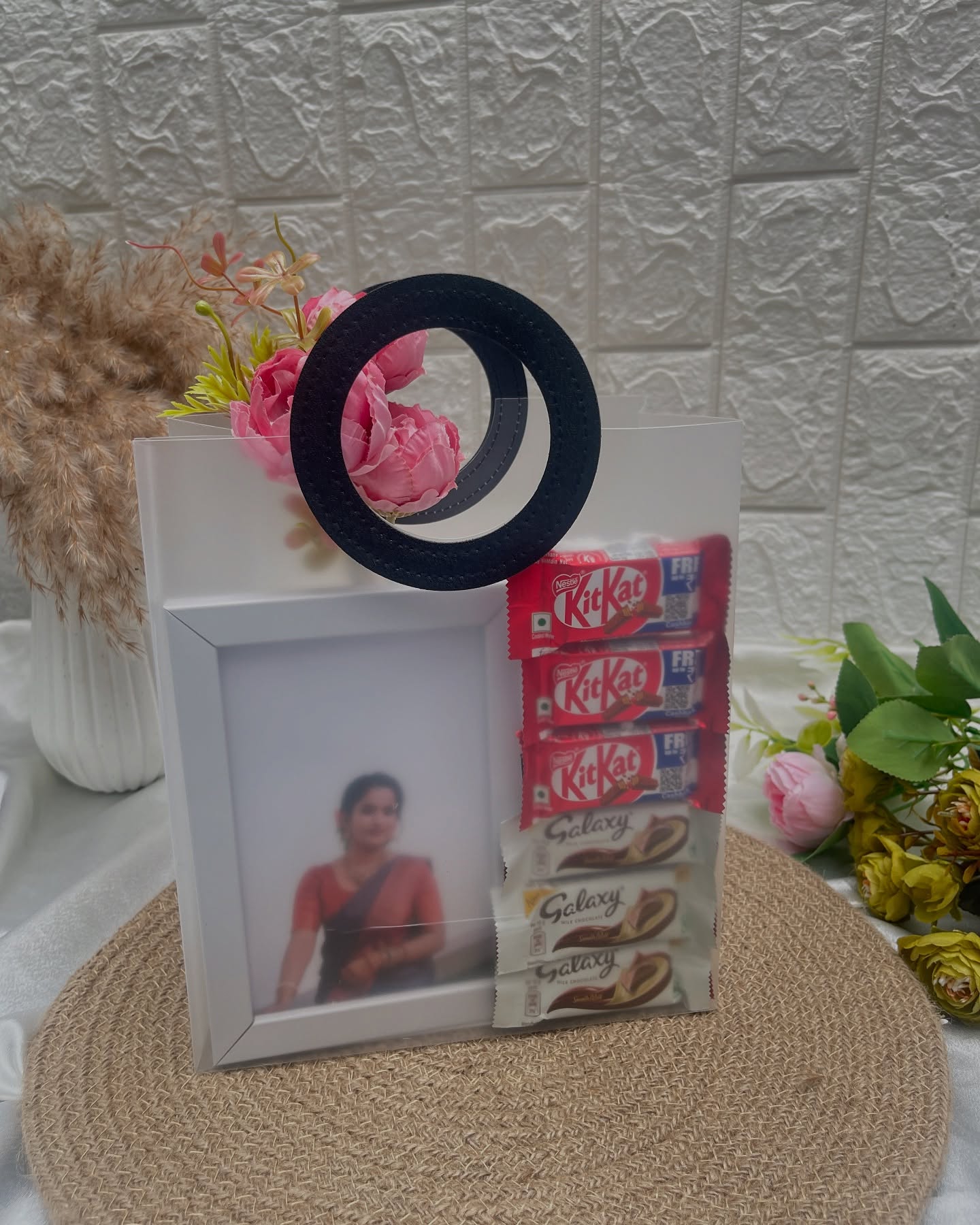 A personalized photo frame paired with KitKat and Galaxy chocolate bars and pink floral accents.