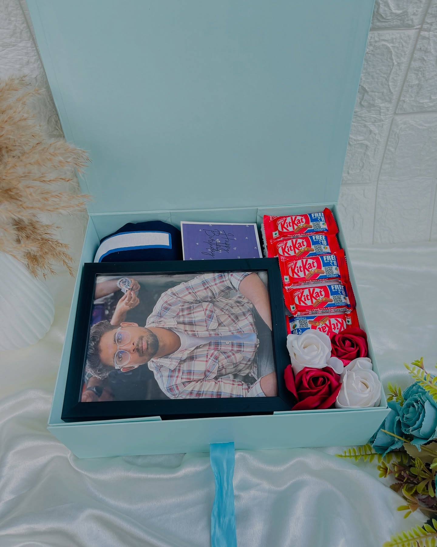 A pastel birthday gift box with a custom photo frame, KitKat bars, roses and a handwritten birthday card.