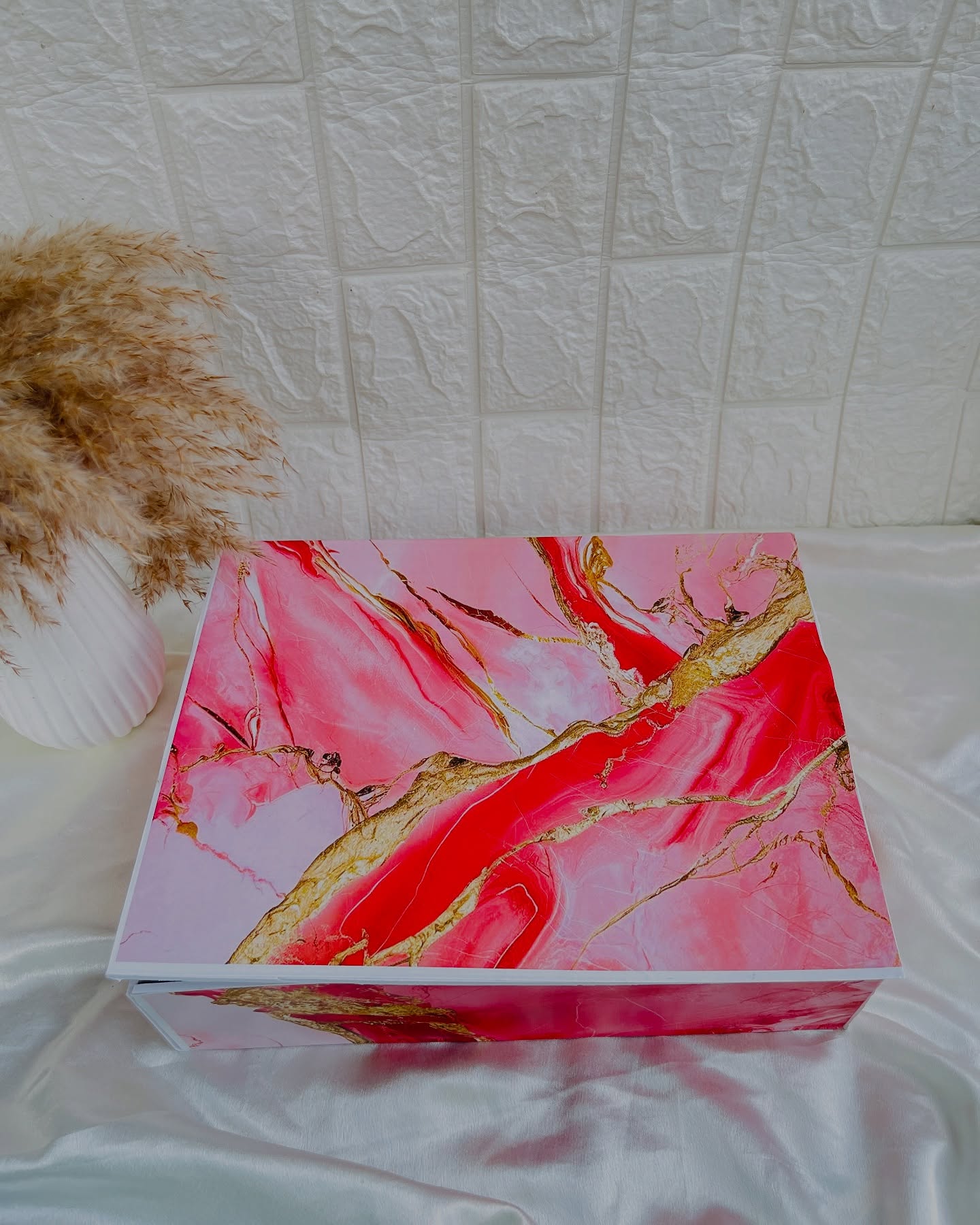 A statement gift box finished in a bold pink and gold marble design, ready to hold a curated surprise inside.