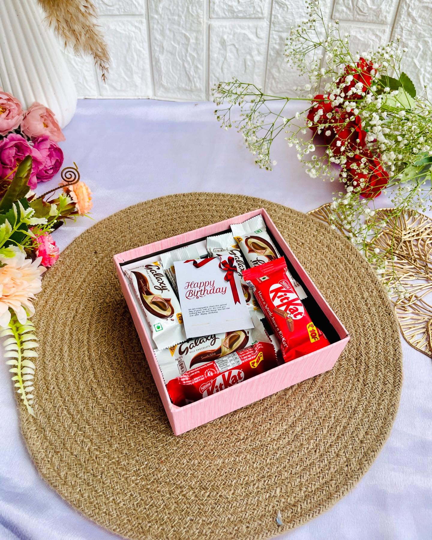 A pretty pink gift box filled with Galaxy chocolate bars, tied with a satin bow and a Happy Birthday card.