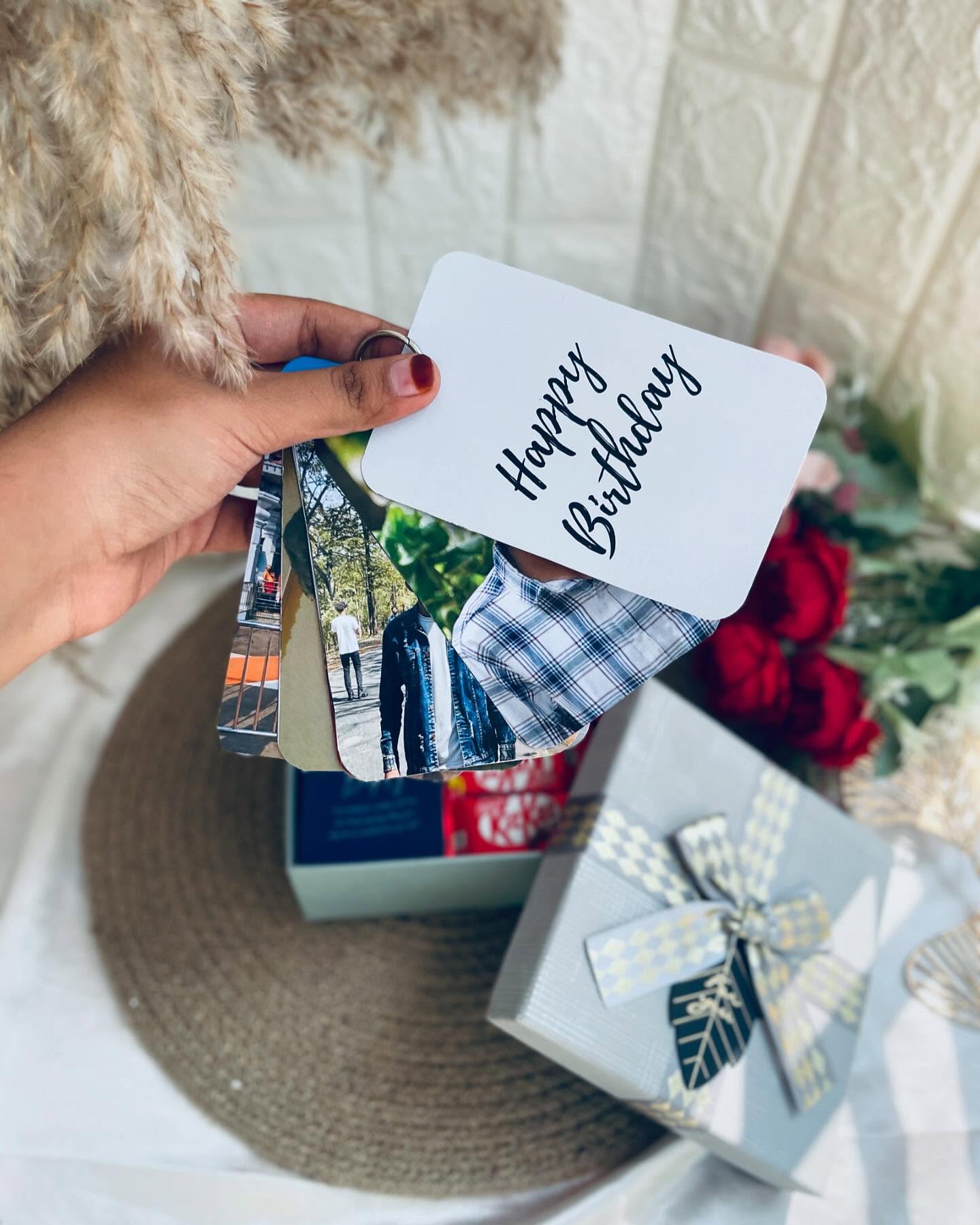 A small textured white photo frame personalized with a 'Happy Birthday' photo, paired with a wrapped gift box tied in a printed bow.