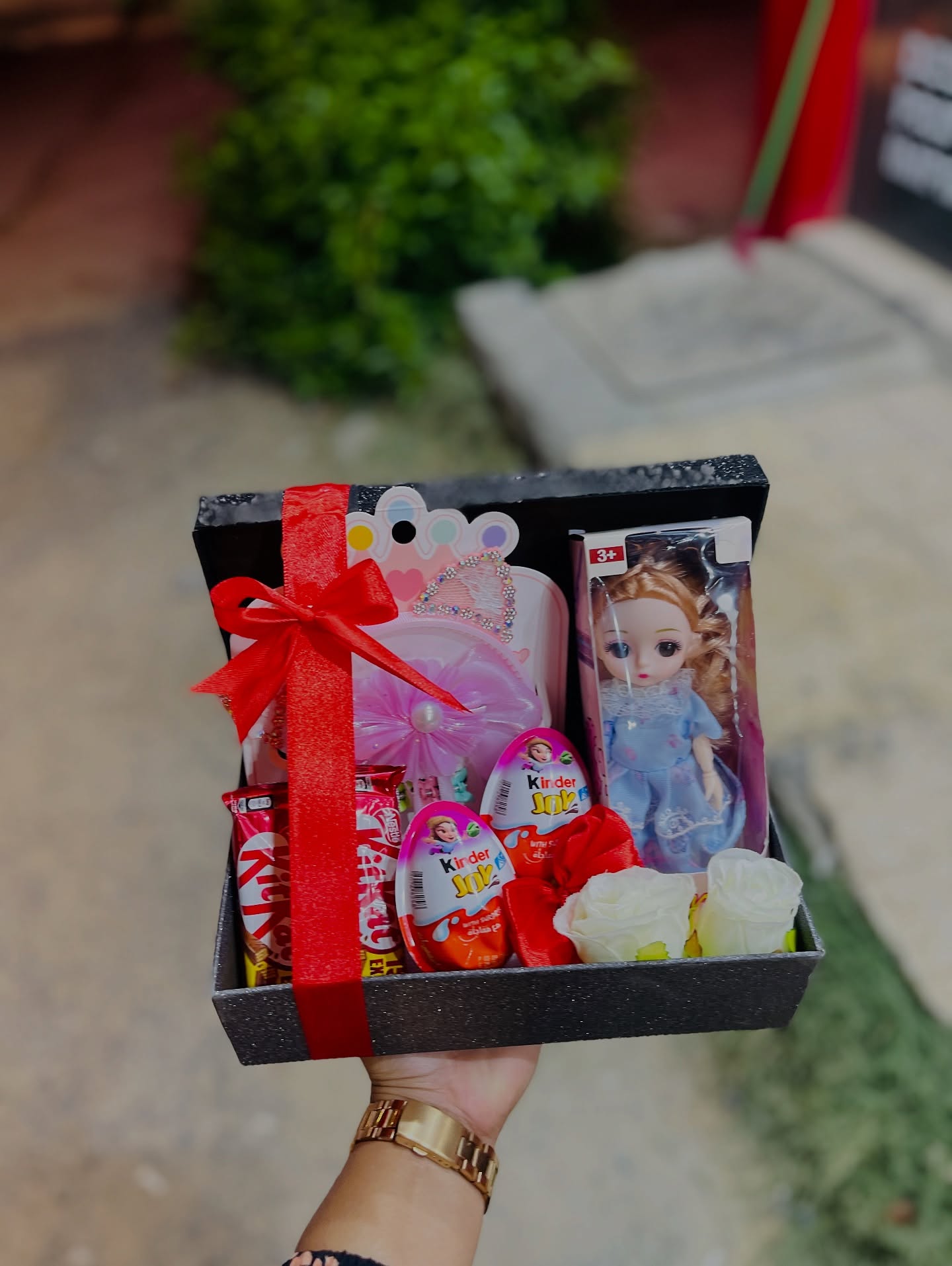 A sparkly black gift box for a little princess, filled with a doll, tiara, Kinder Joy eggs and KitKat treats.