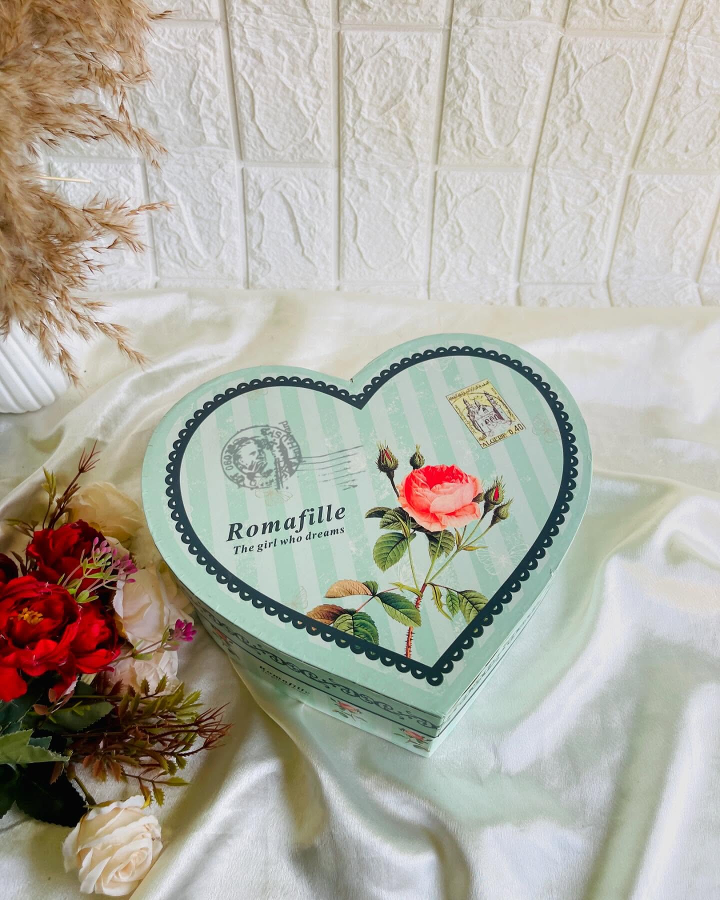A vintage-style mint heart-shaped gift box with a romantic rose print, perfect for sweet surprises.