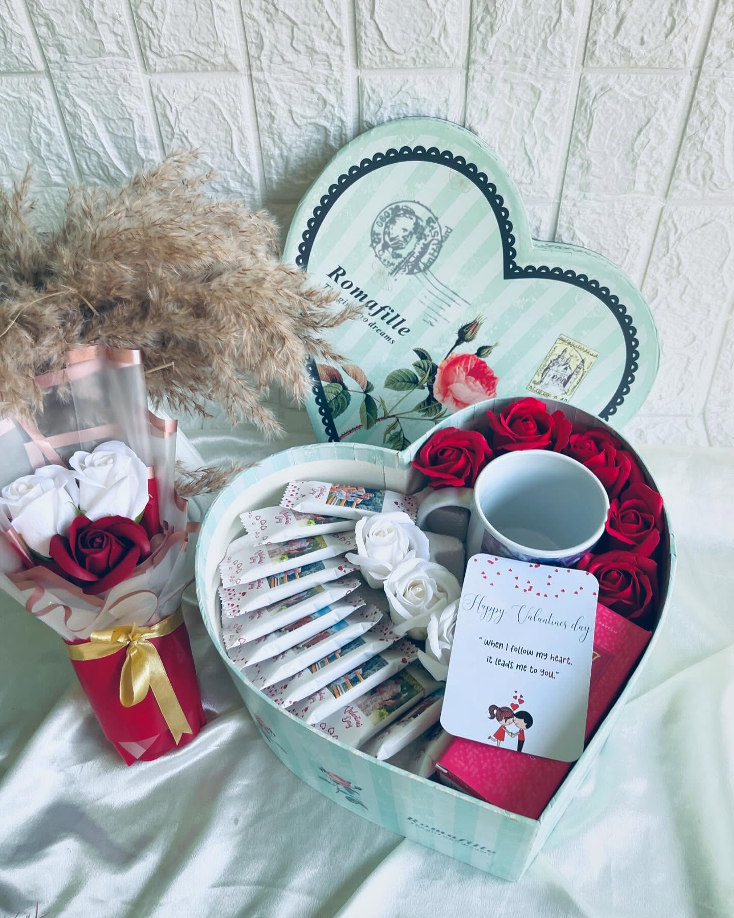 A heart-shaped keepsake box filled with roses, a mug, chocolates, and personalized photo notes.