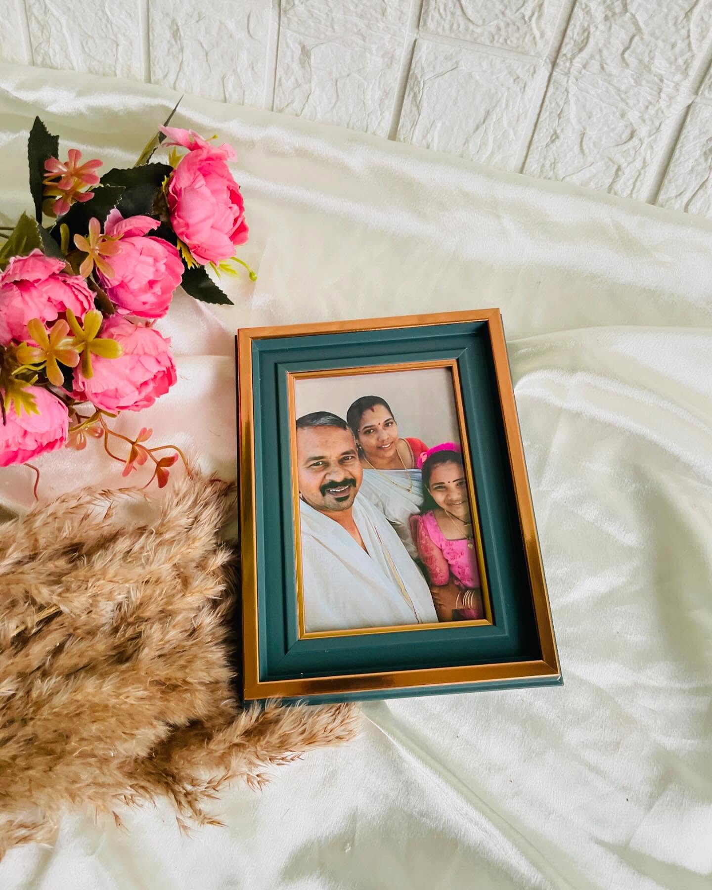A teal and gold photo frame styled with blush pink roses, perfect for showcasing a cherished family portrait.
