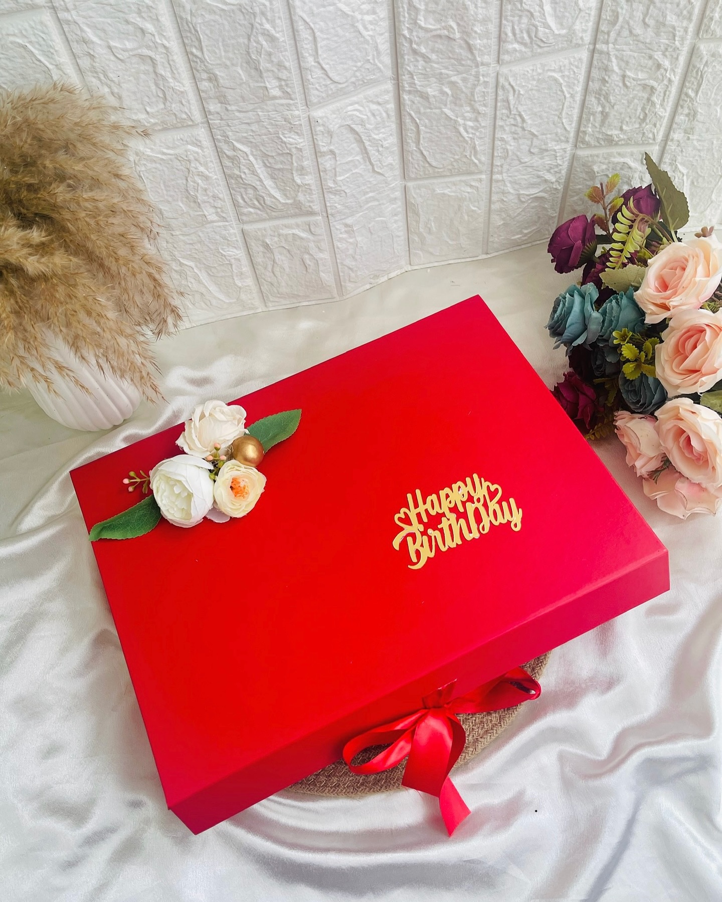 An elegant red gift box finished with a floral accent and a satin bow for a memorable birthday surprise.
