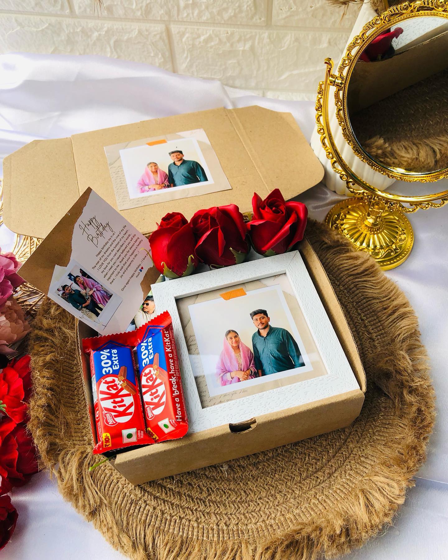 A keepsake birthday box with a personalized photo frame, fresh red roses, and KitKat bars for someone special.