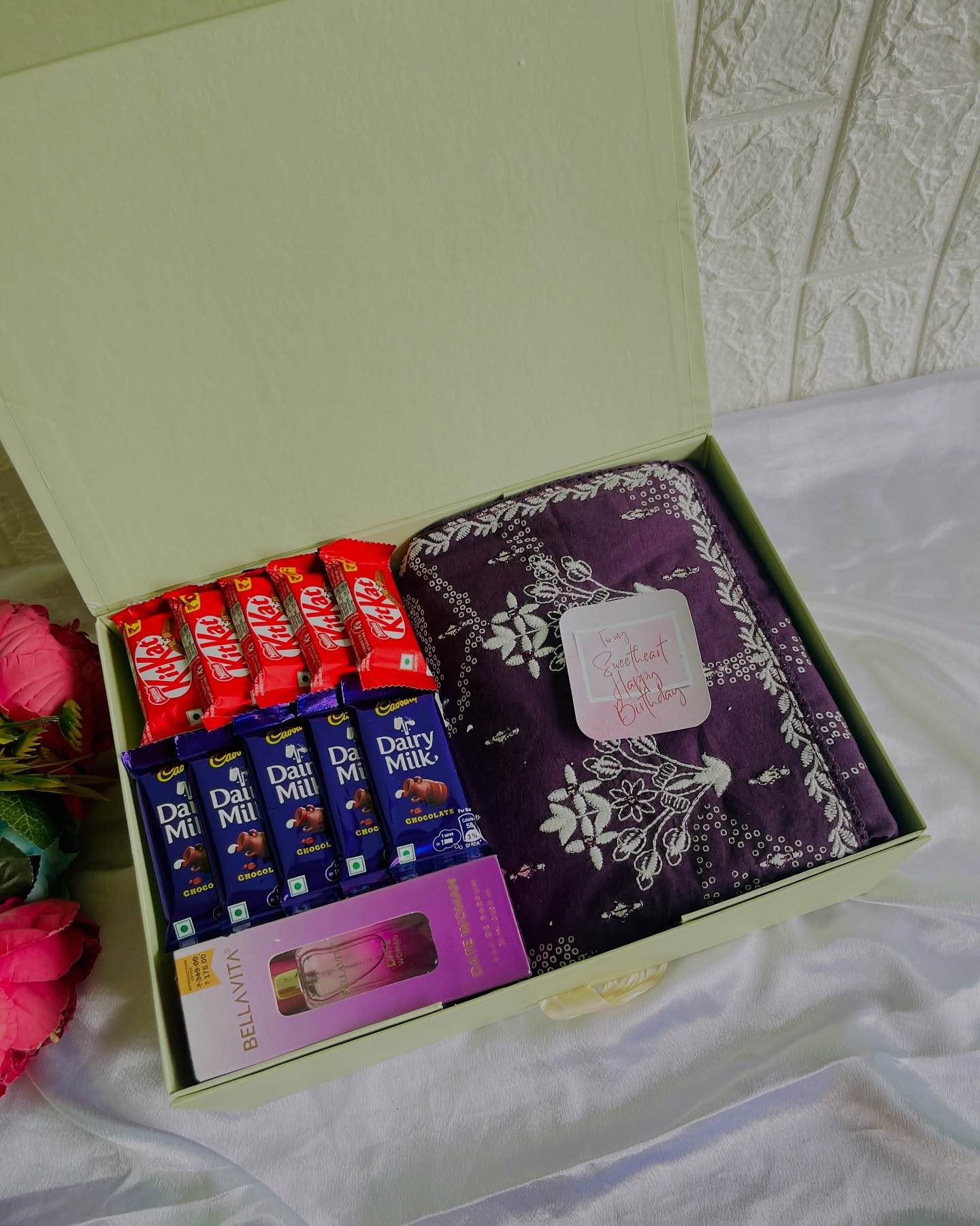 An elegant gift box featuring a traditional embroidered saree paired with Cadbury and KitKat chocolates and a mini perfume.
