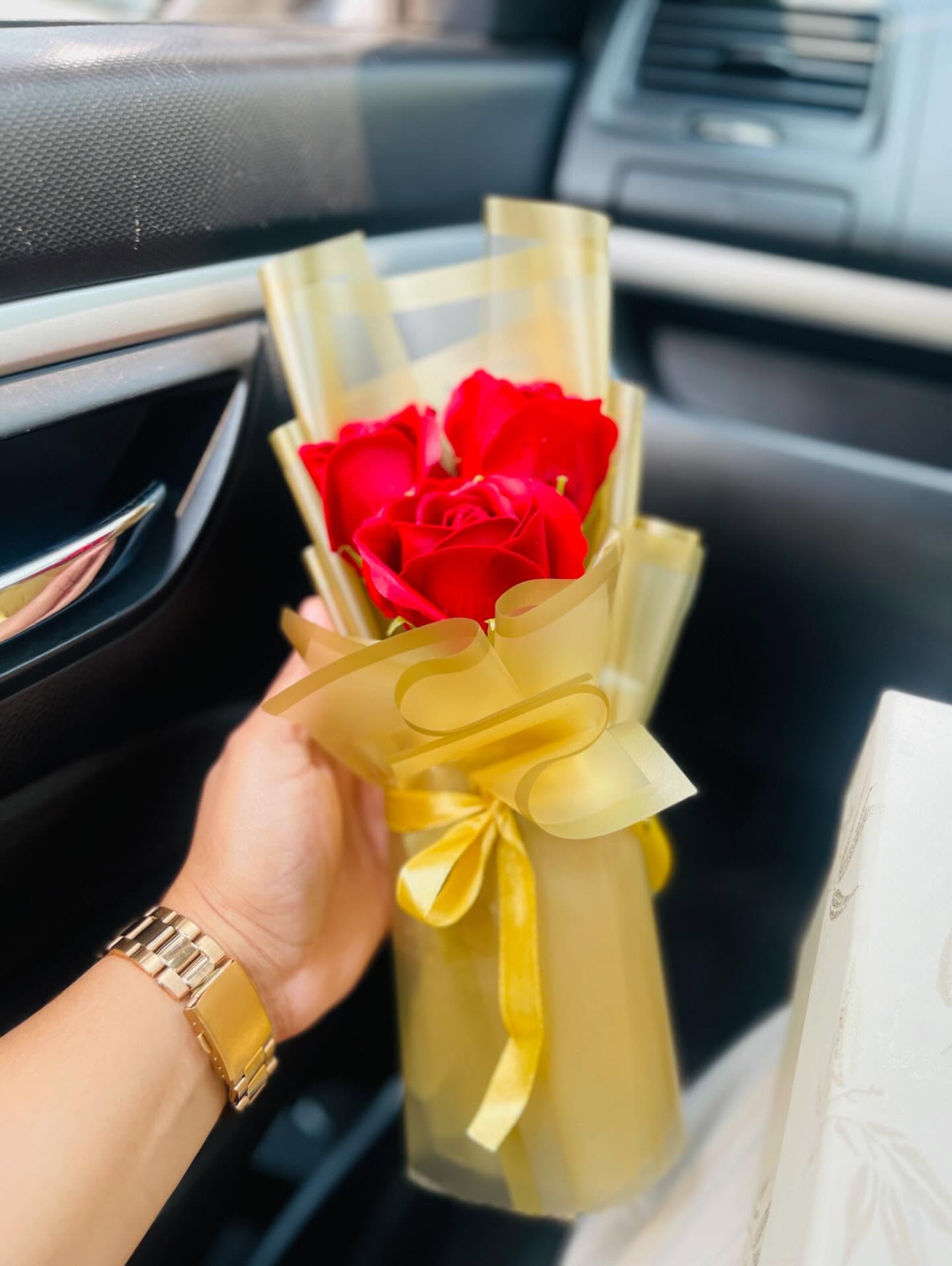 Three fresh red roses wrapped in elegant gold cellophane, a simple romantic gesture for any occasion.
