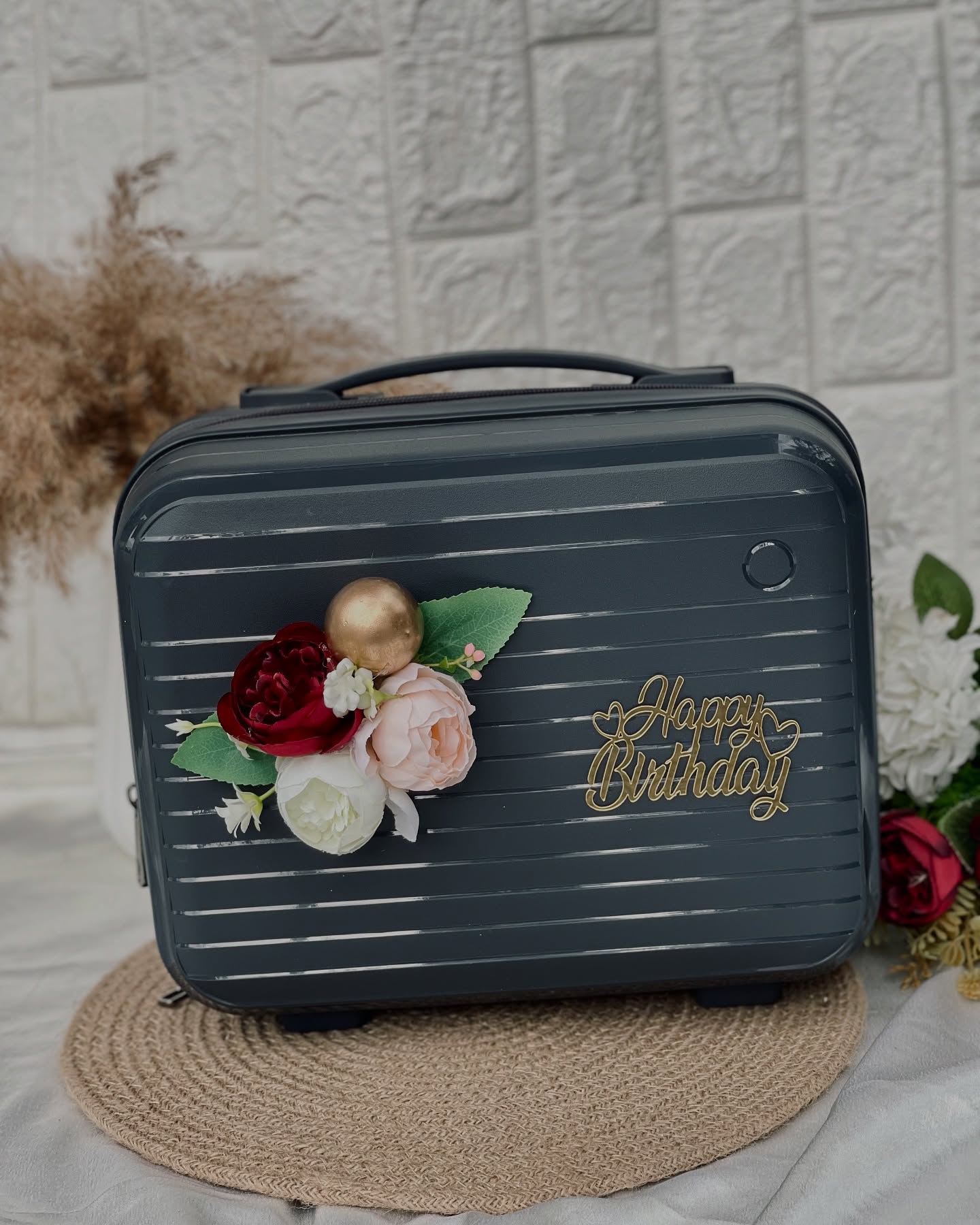A charcoal grey vanity case styled with burgundy and blush roses and a gold Happy Birthday topper.