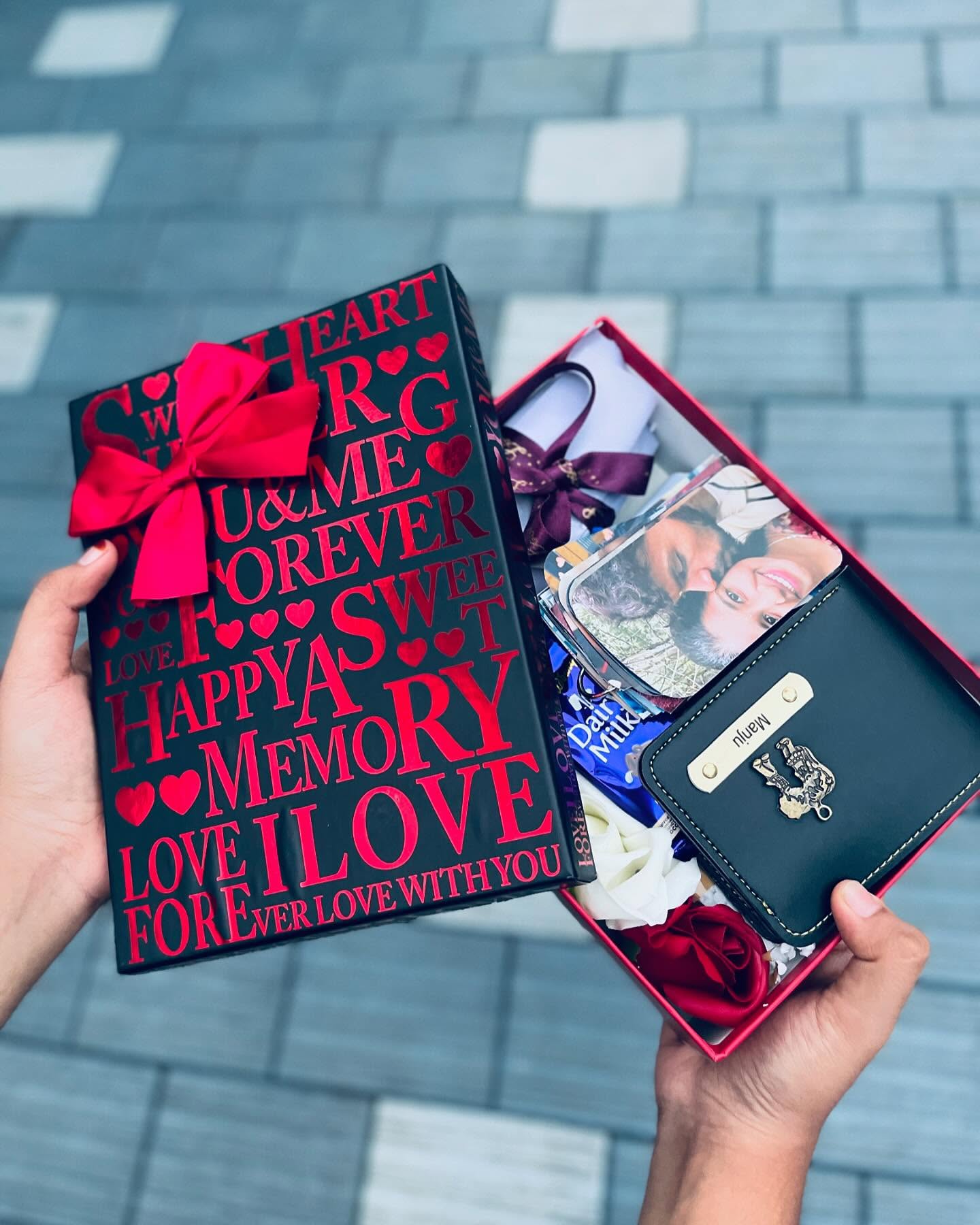 A romantic love-themed gift box filled with a personalized wallet, photo strip, roses, and chocolate.