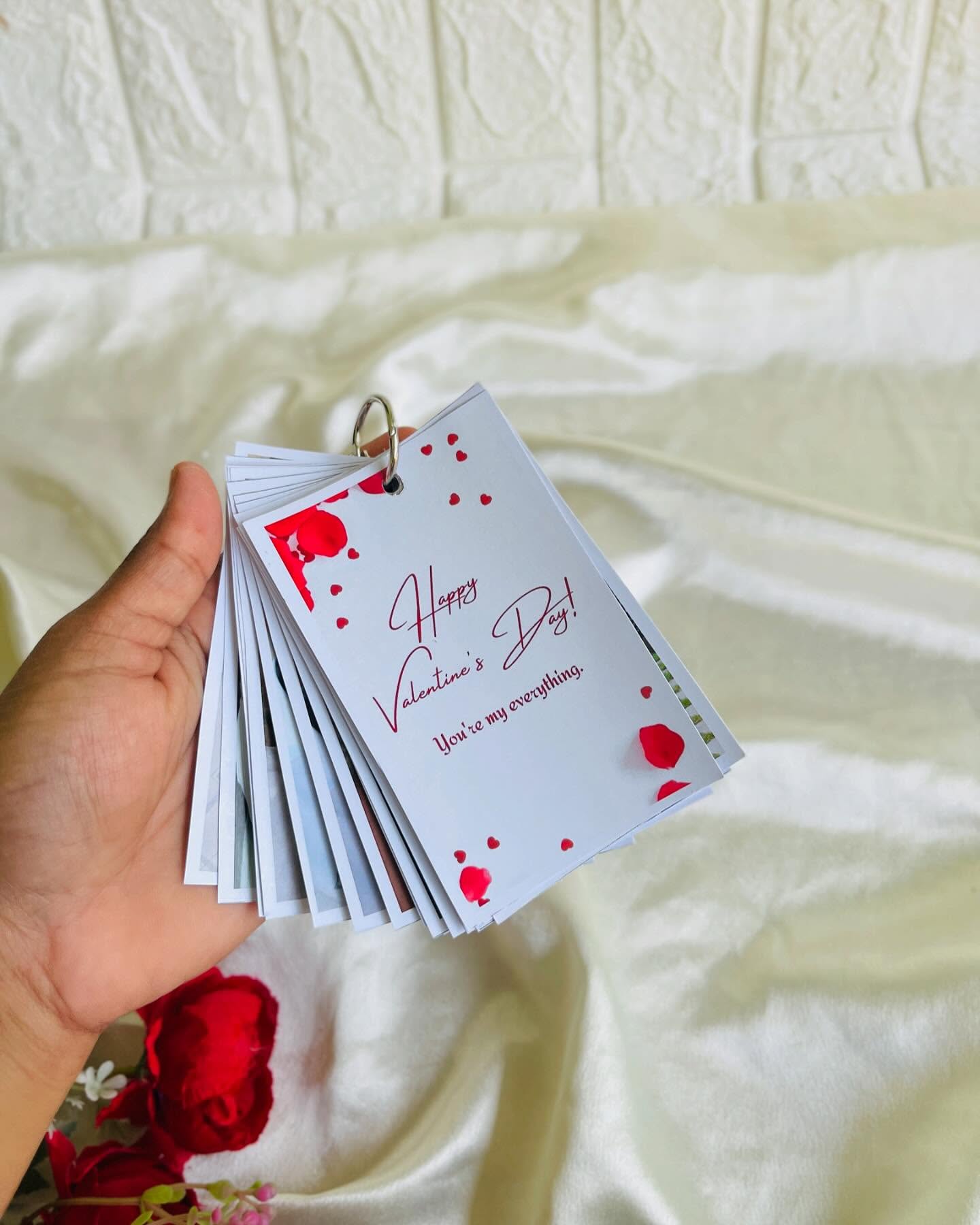 A ring-bound mini flip book of couple photos topped with a printed Valentine's message card.