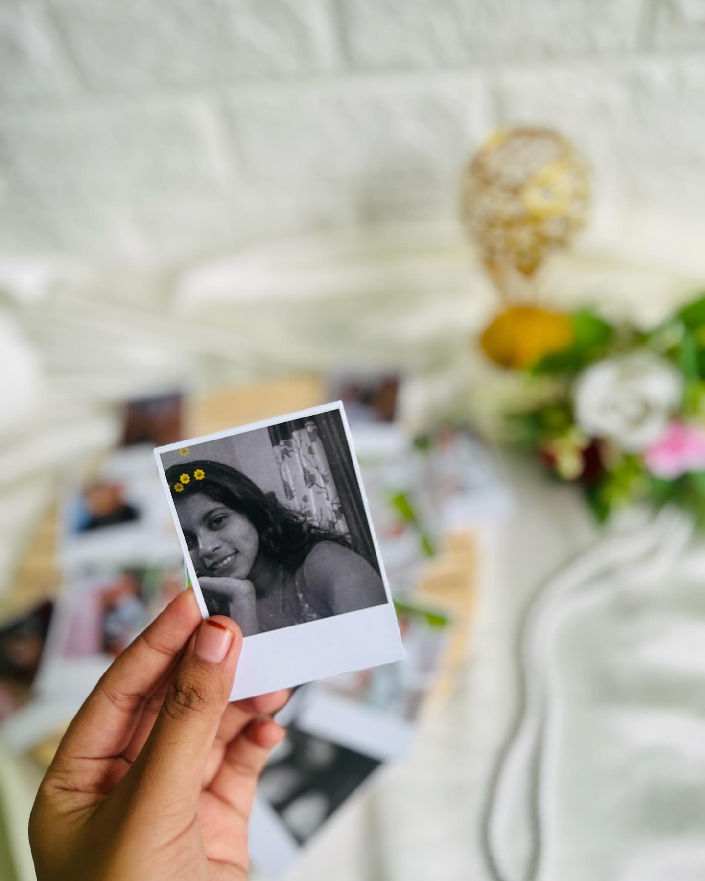 A set of personalized black-and-white polaroid-style prints tucked among fresh blooms for a nostalgic keepsake gift.
