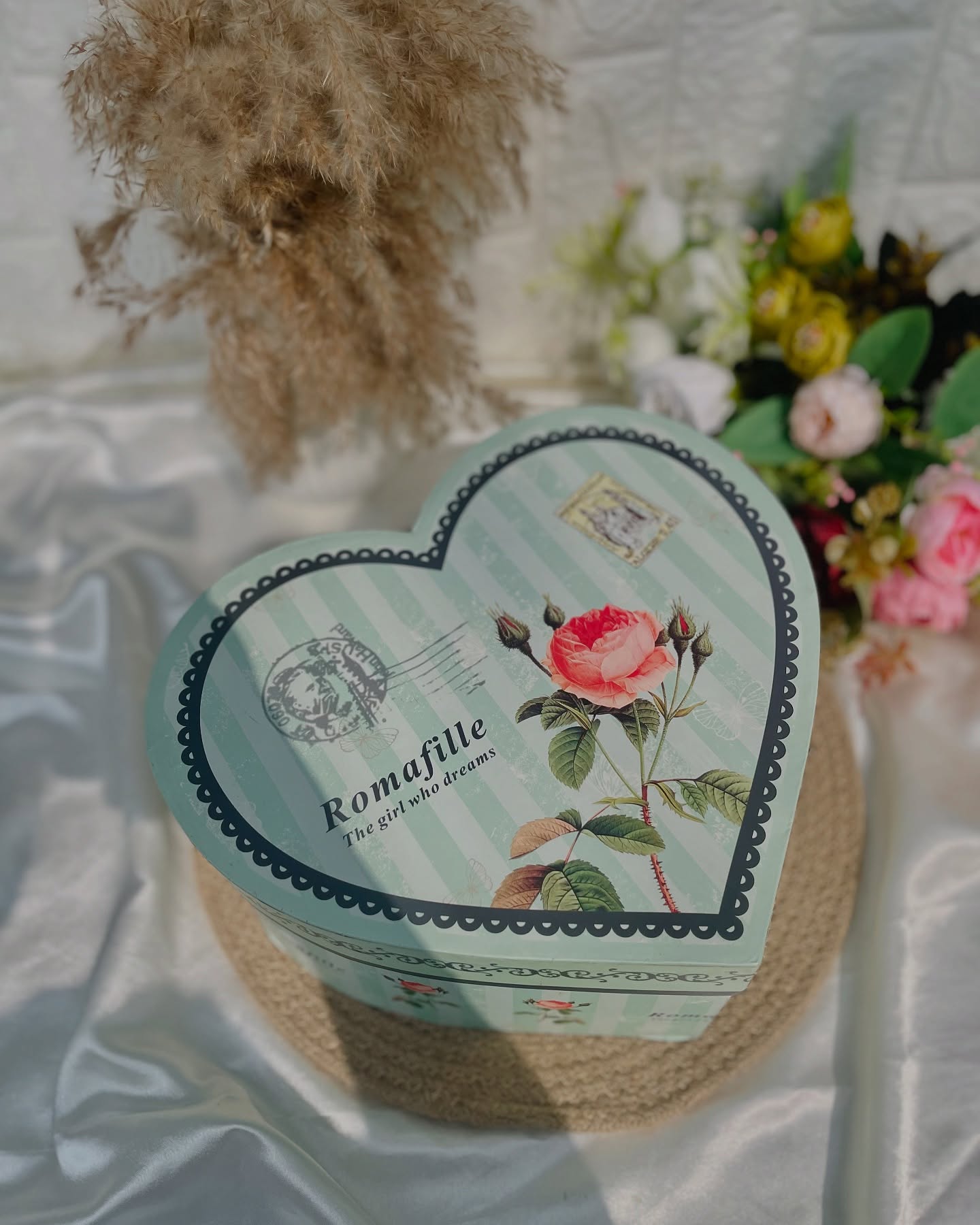 A charming heart-shaped tin gift box adorned with a vintage rose and postcard-style print, perfect for a romantic surprise.