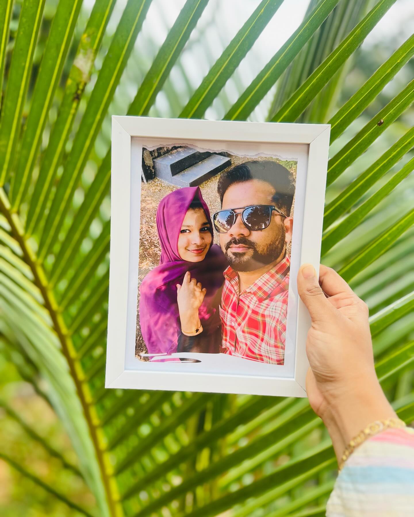 A framed couple photo finished with a creative torn-paper double exposure effect, shown outdoors.