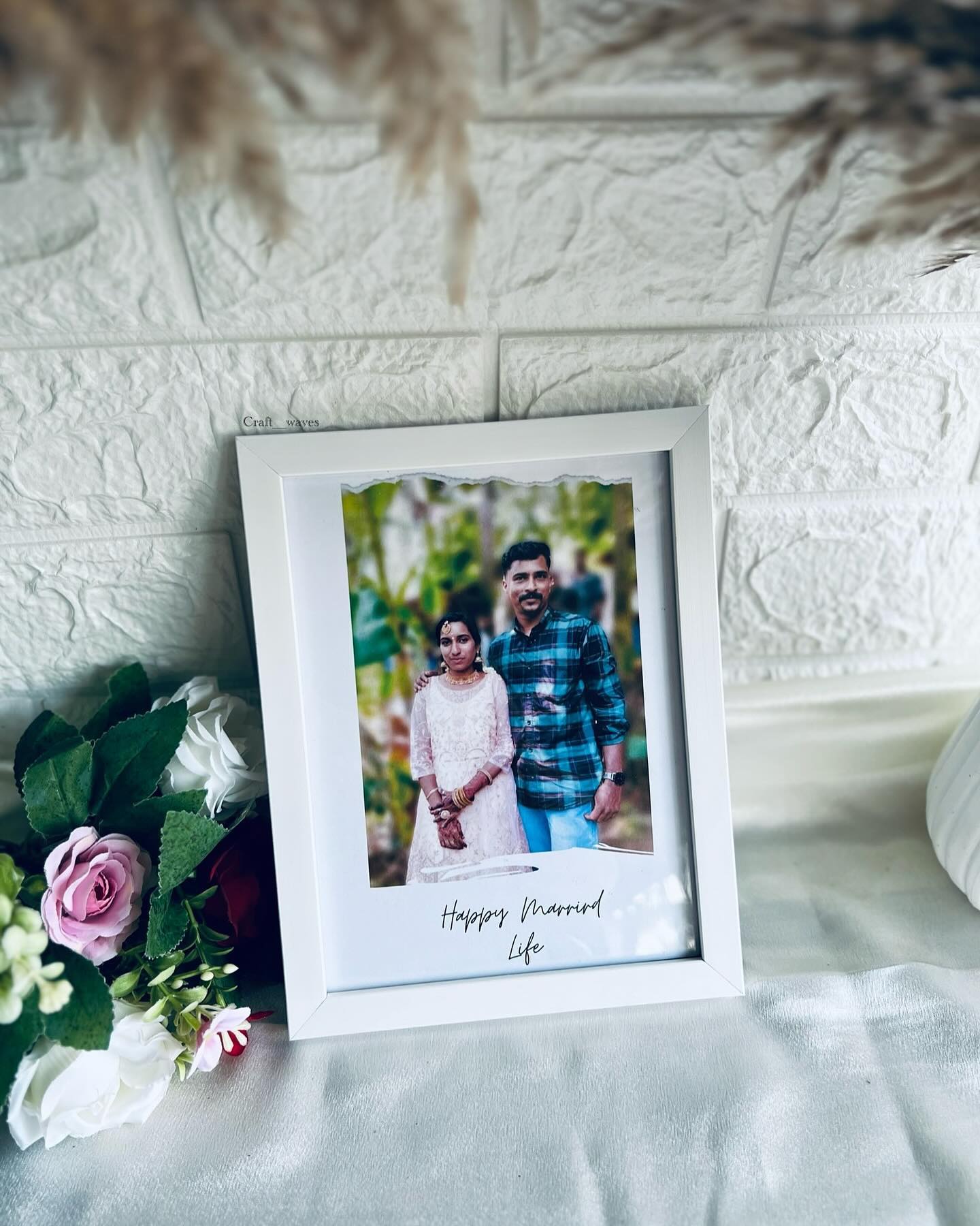 A white photo frame with a torn-paper style print of a wedding couple photo and a 'Happy Married Life' message.