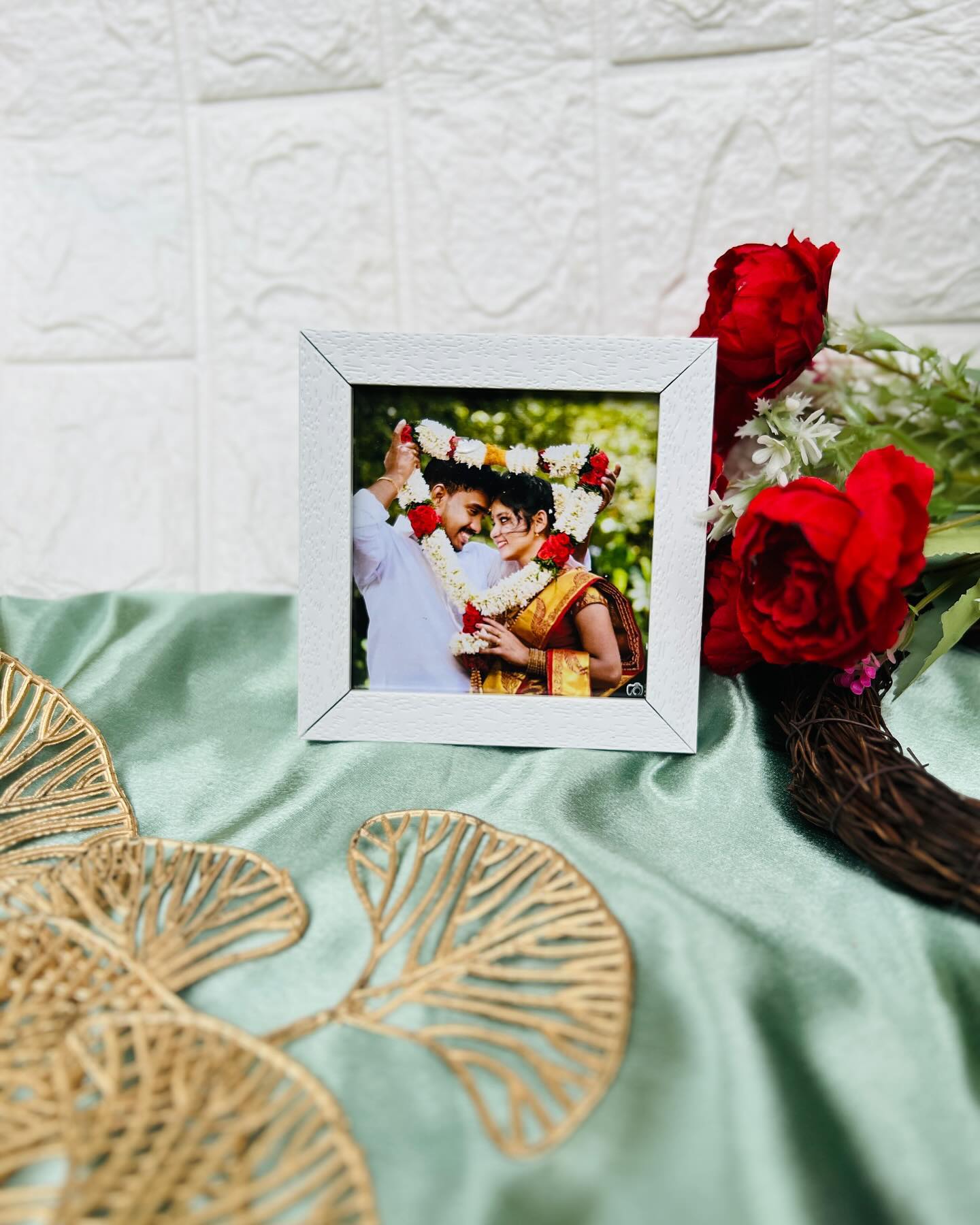 A textured white photo frame showcasing a couple's traditional wedding garland moment.
