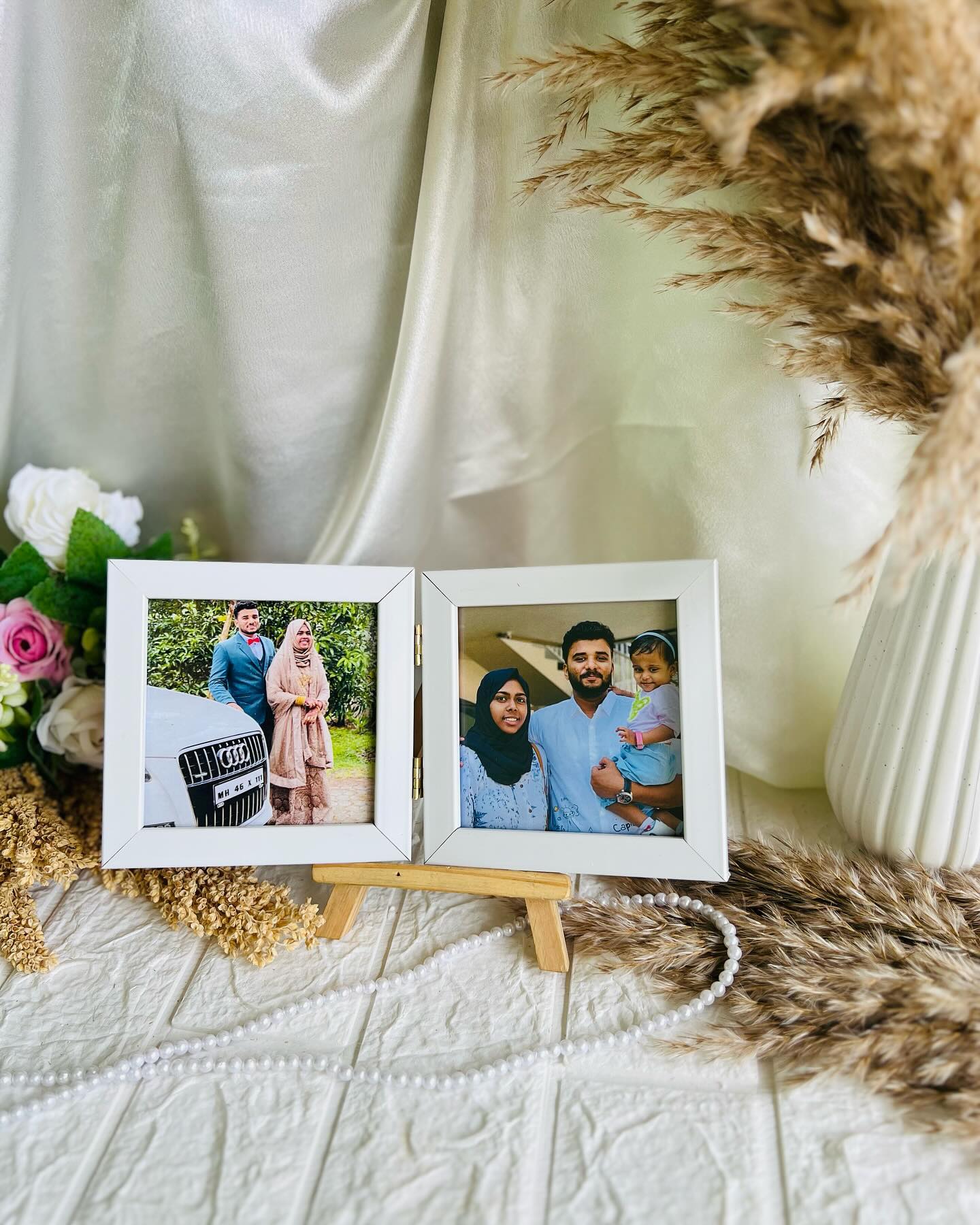 A pair of mini white photo frames on a wooden easel stand, showcasing wedding and family portraits side by side.