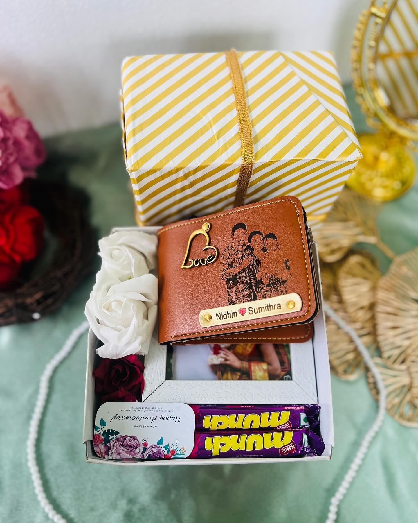 A festive yellow-wrapped anniversary box with a personalised wedding photo frame, Munch chocolates, and fresh roses.