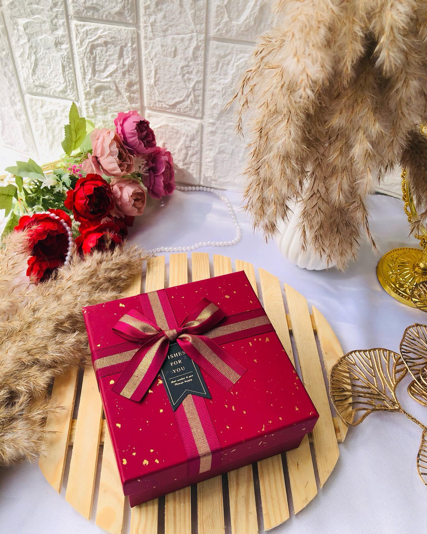 An elegant maroon and gold gift box tied with a satin ribbon bow, ready for any celebration.